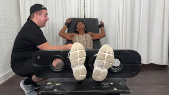 Tickling Lady Phoenix in the Tickling Chair's Stocks While She Laughs and Fights Back.webp
