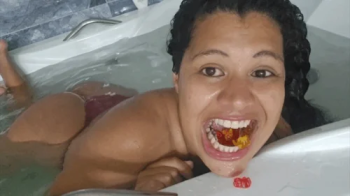 Giantess devouring gummy bears in the bathtub.webp