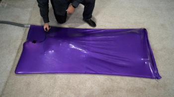 A girl experiences an orgasm in a lilac vacuum bed with an inflatable gag in her mouth.webp