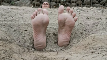 Buried on the beach with only my feet and head outside, my soles are tickled a lot (C3).webp